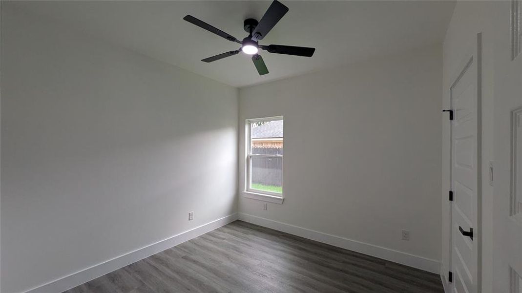 Unfurnished bedroom with dark wood-type flooring, baseboards, and ceiling fan