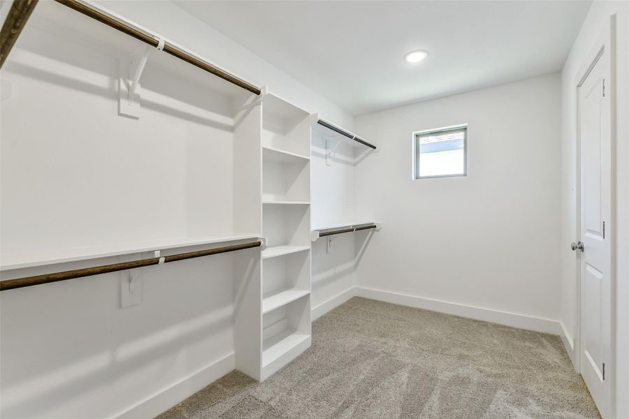 Expansive walk-in closet with built-in shelving, double hanging rods and an added accent window that brings in natural light.