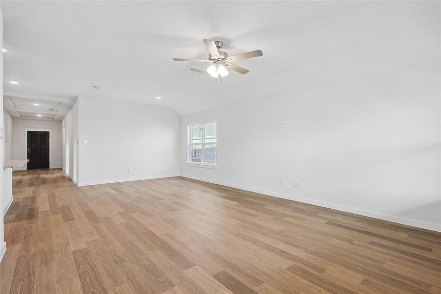 Empty room featuring ceiling fan, vaulted ceiling, and light hardwood / wood-style flooring