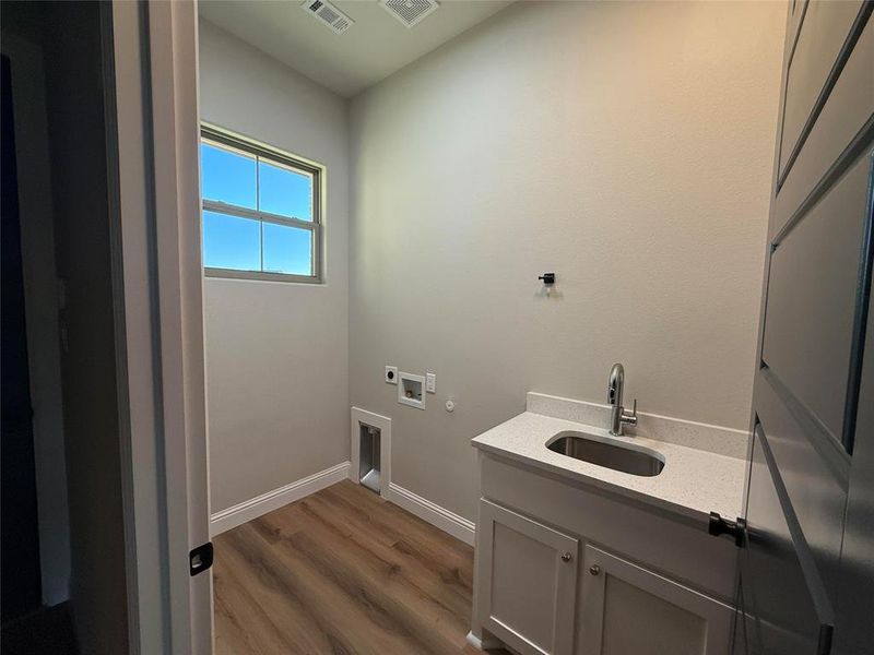 Washroom with hookup for a gas dryer, dark wood finished floors, hookup for an electric dryer, cabinet space, and washer hookup Washroom with hookup for a gas dryer, dark wood finished floors, hookup for an electric dryer, cabinet space, and washer hookup