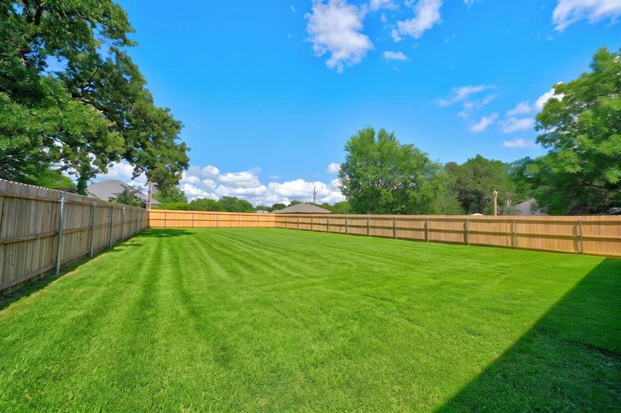 Expansive green lawn with a full privacy fence