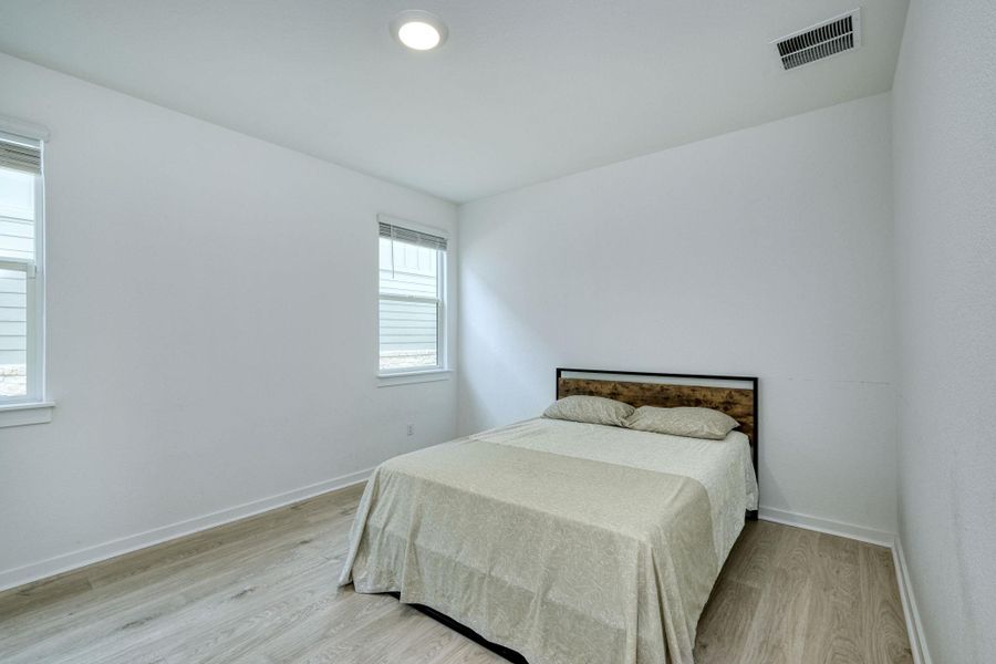 Bedroom featuring light wood-type flooring, visible vents, and baseboards