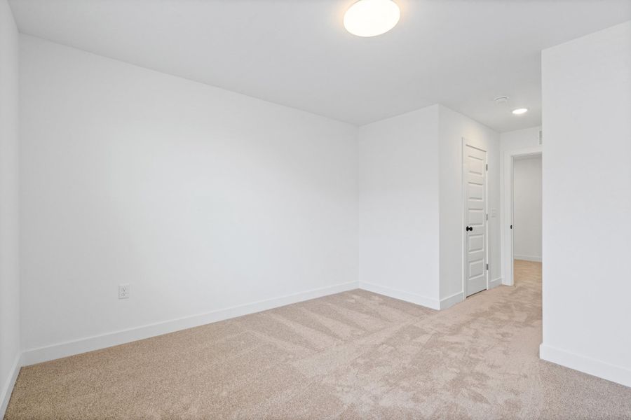 Neutral-toned carpeted interior space featuring white walls and baseboards Neutral-toned carpeted interior space featuring white walls and baseboards