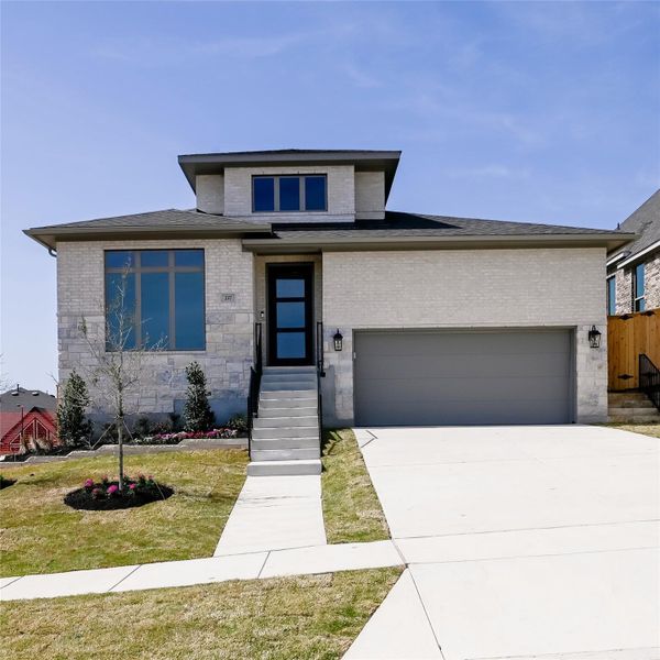 Prairie-style home with driveway, an attached garage, and brick siding Prairie-style home with driveway, an attached garage, and brick siding