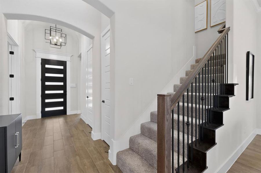Foyer featuring wood-look tile flooring, an arched entryway, and a modern geometric chandelier