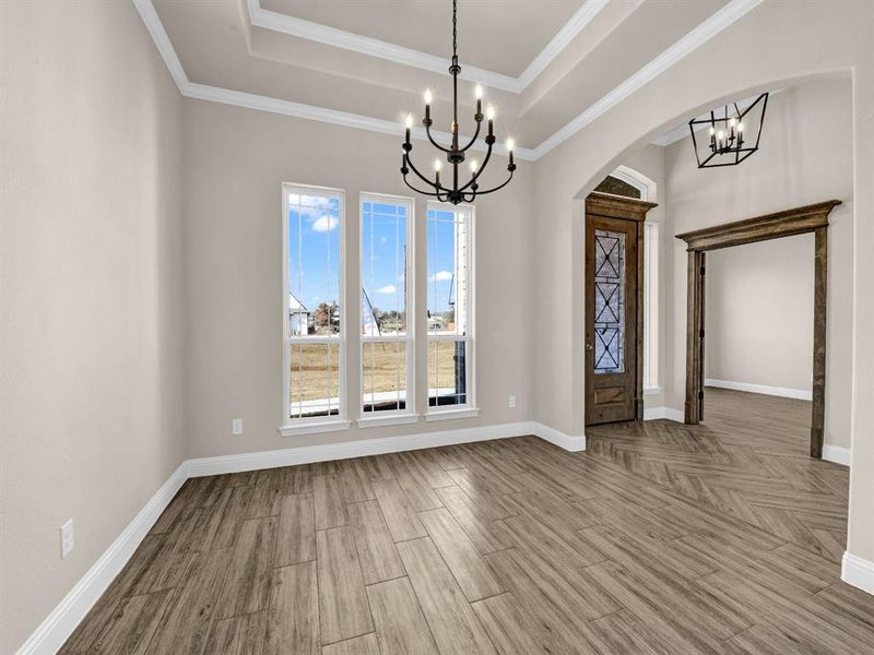 Foyer entrance featuring light hardwood / wood-style floors, an inviting chandelier, a tray ceiling, and crown molding