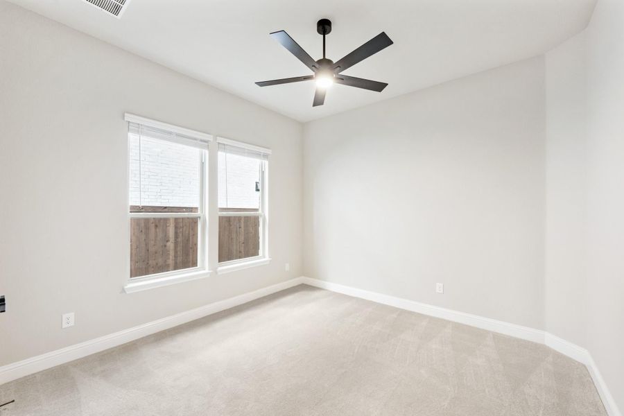Empty bedroom with beige carpet, white walls, ceiling fan, and double window with blinds
