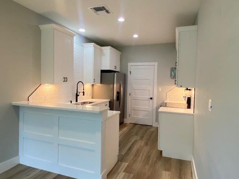 Modern kitchen featuring sleek white cabinetry, a convenient breakfast bar, and new stainless steel appliances. Modern kitchen featuring sleek white cabinetry, a convenient breakfast bar, and new stainless steel appliances.