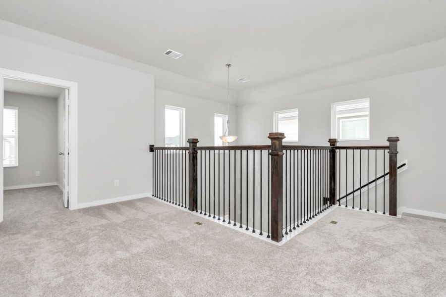 Ascend to relaxation in this fantastic game room! Ideal for both casual gatherings and adult gaming, it boasts plush carpet, lofty ceilings, custom paint, and ample windows for abundant natural light. Sample photo of completed home with similar floor plan. Actual colors and selections may vary.