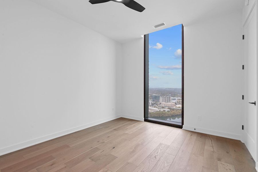 Room with light wood-style floors, expansive windows, a city view, and ceiling fan