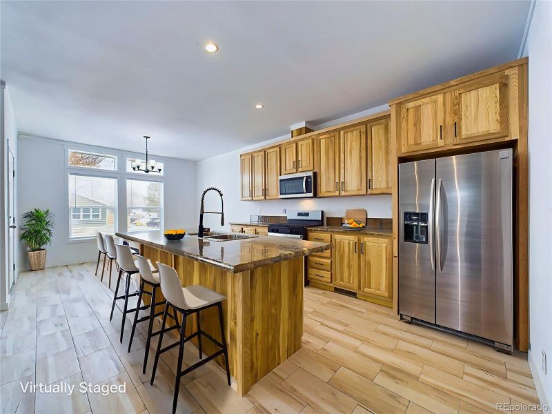 Kitchen featuring sink, maple cabinets, a kitchen island with sink, and appliances with stainless steel finishes...