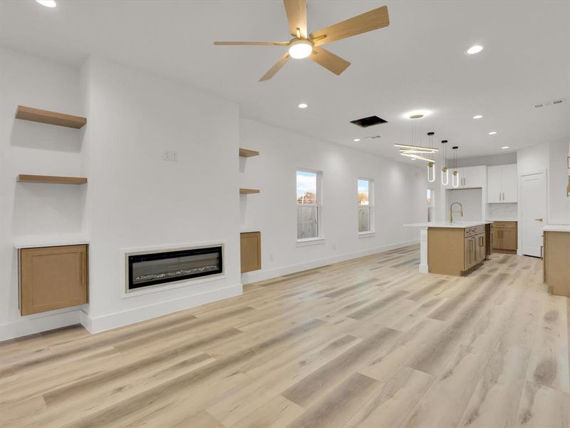 Unfurnished living room with ceiling fan, sink, and light hardwood / wood-style flooring