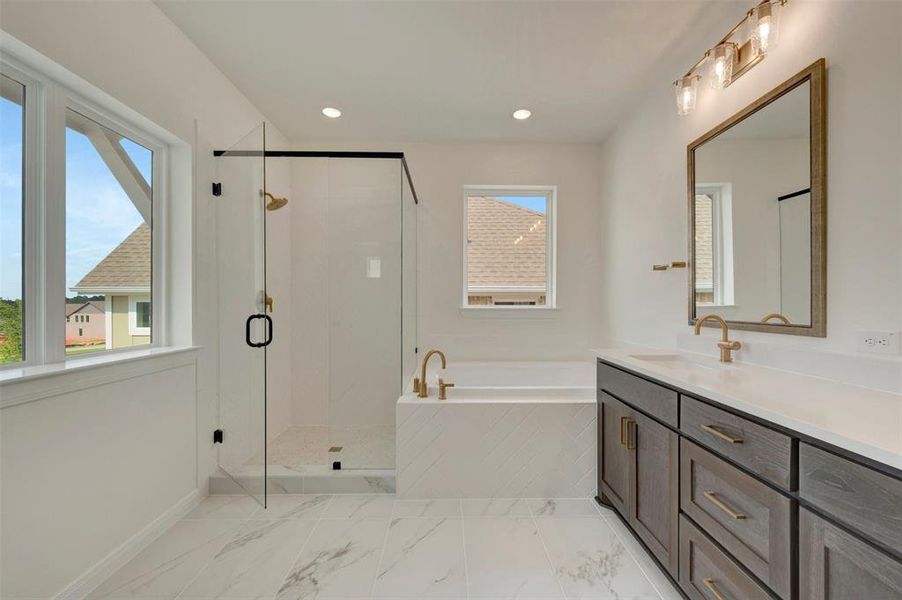 Spacious bathroom featuring a frameless glass shower enclosure, a built-in soaking tub with white subway tile surround, a double vanity with stone countertop, and large format marble-look floor tiles