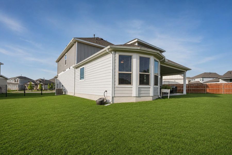 A neatly maintained lawn surrounds the modern home with a covered patio for outdoor enjoyment. A neatly maintained lawn surrounds the modern home with a covered patio for outdoor enjoyment.
