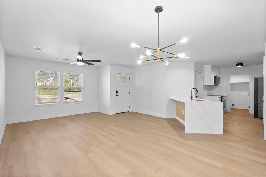 Kitchen featuring sink, white cabinets, kitchen peninsula, light stone countertops, and pendant lighting