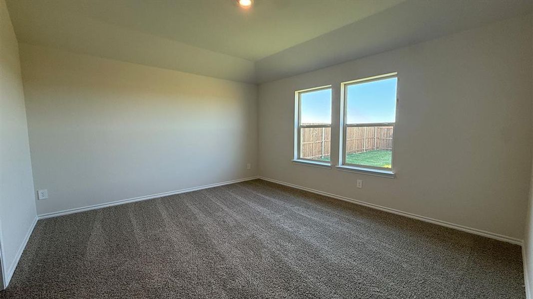 Spacious room featuring neutral carpet, two large windows, white trim, and a tray ceiling