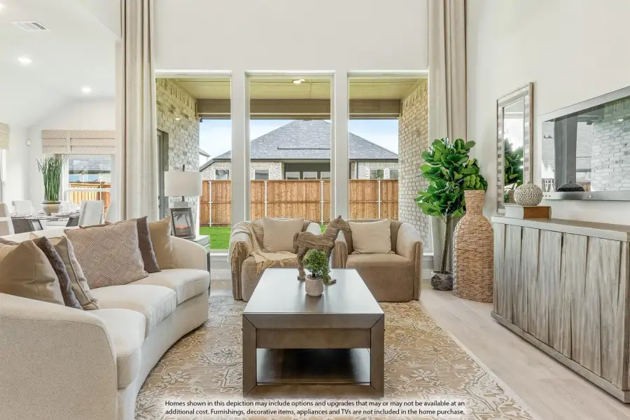 Open living room with high ceilings, large windows, neutral sofas, and wood coffee table on patterned rug Open living room with high ceilings, large windows, neutral sofas, and wood coffee table on patterned rug