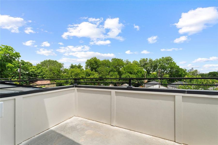Rooftop patio featuring a concrete surface, white paneled walls, and a black metal railing