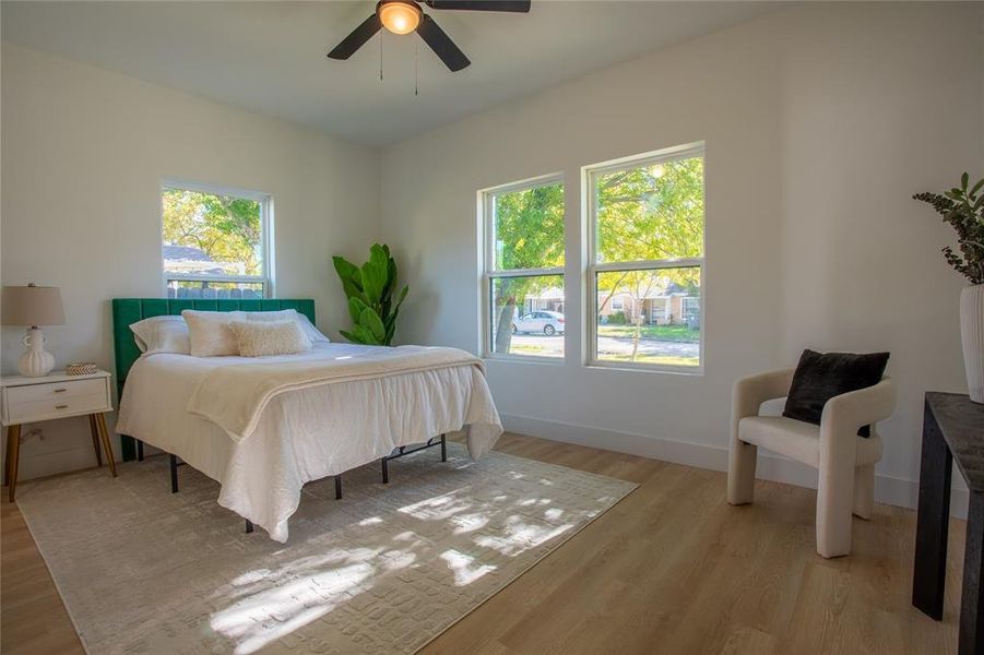 Bedroom with light hardwood / wood-style floors, multiple windows, and ceiling fan