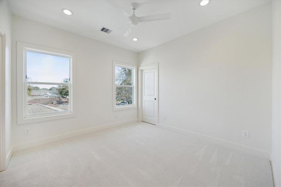 Soft carpeting and a neutral palette make this secondary bedroom a welcoming and versatile space. Large windows provide an open and airy feel, complemented by recessed lighting and a modern ceiling fan. The closet offers ample storage, while the Jack and Jill bathroom, shared with the adjacent bedroom, is conveniently attached. This room is perfectly suited for family members, guests, or a home office.