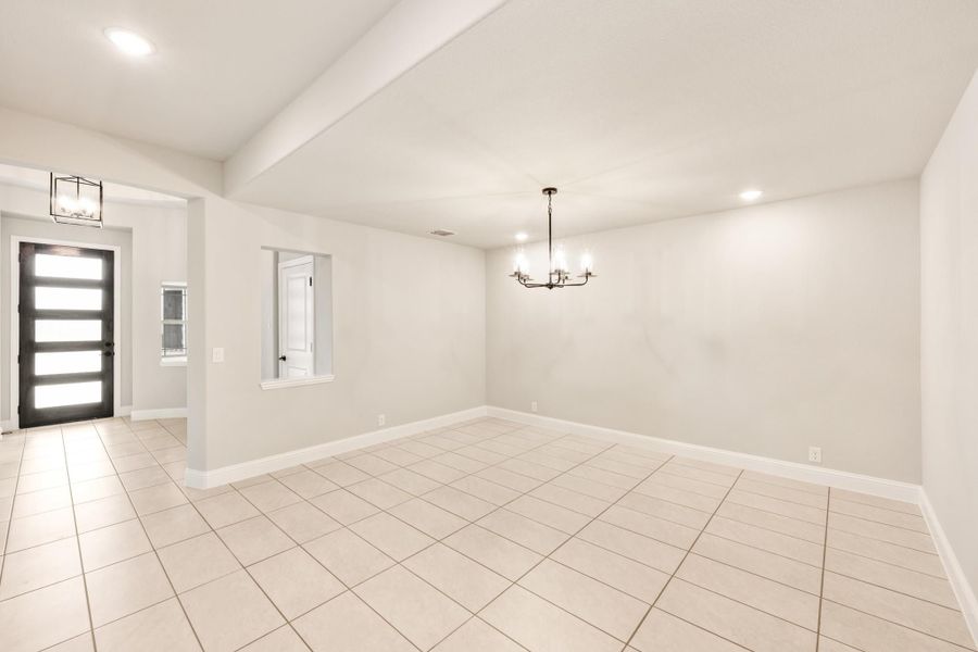 Empty dining room with white tile floors, chandelier, and modern front door entry visible Empty dining room with white tile floors, chandelier, and modern front door entry visible