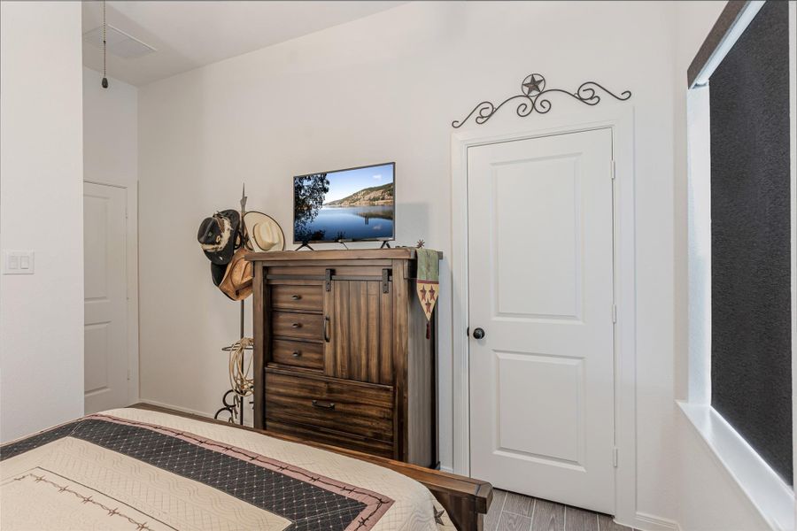 Another view of guest bedroom showing the door for closet and to the left is the bathroom and door leaving back to the hallway.