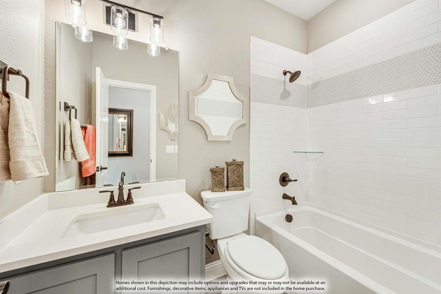 Bathroom with white subway tile tub surround, gray vanity, white countertop, and bronze fixtures