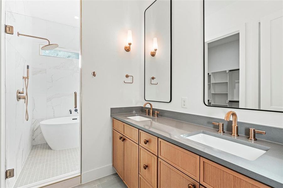 Full bath featuring double vanity, a marble finish shower, light tile patterned floors, a freestanding bath, and a spacious closet