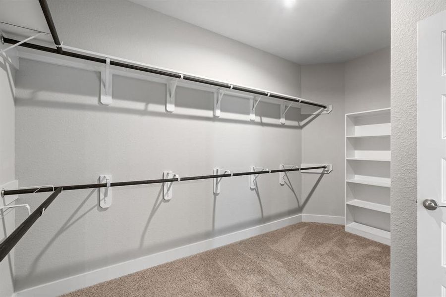 Immerse yourself in the lap of luxury within this roomy walk-in closet boasting high ceilings and plush carpeting. Sample photo of completed home with similar floor plan. As-built interior colors and selections may vary.