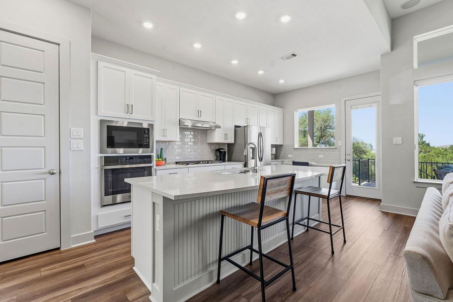 Kitchen with white cabinets, a center island with sink, stainless steel appliances, dark wood finished floors, and a breakfast bar area Kitchen with white cabinets, a center island with sink, stainless steel appliances, dark wood finished floors, and a breakfast bar area