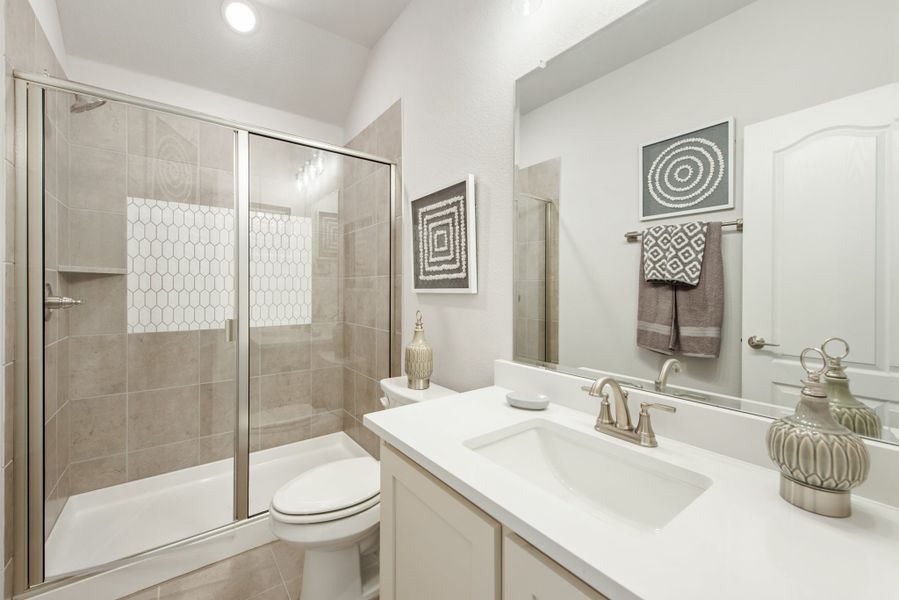 Bathroom with glass-door shower, white quartz vanity, single sink, and toilet in neutral tones