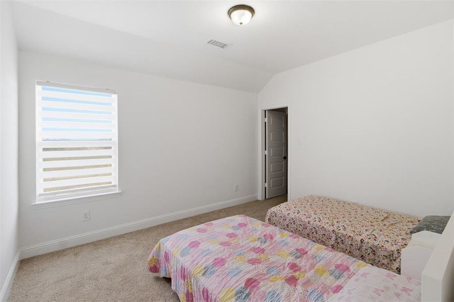 Bedroom featuring a vaulted ceiling and neutral-toned carpet