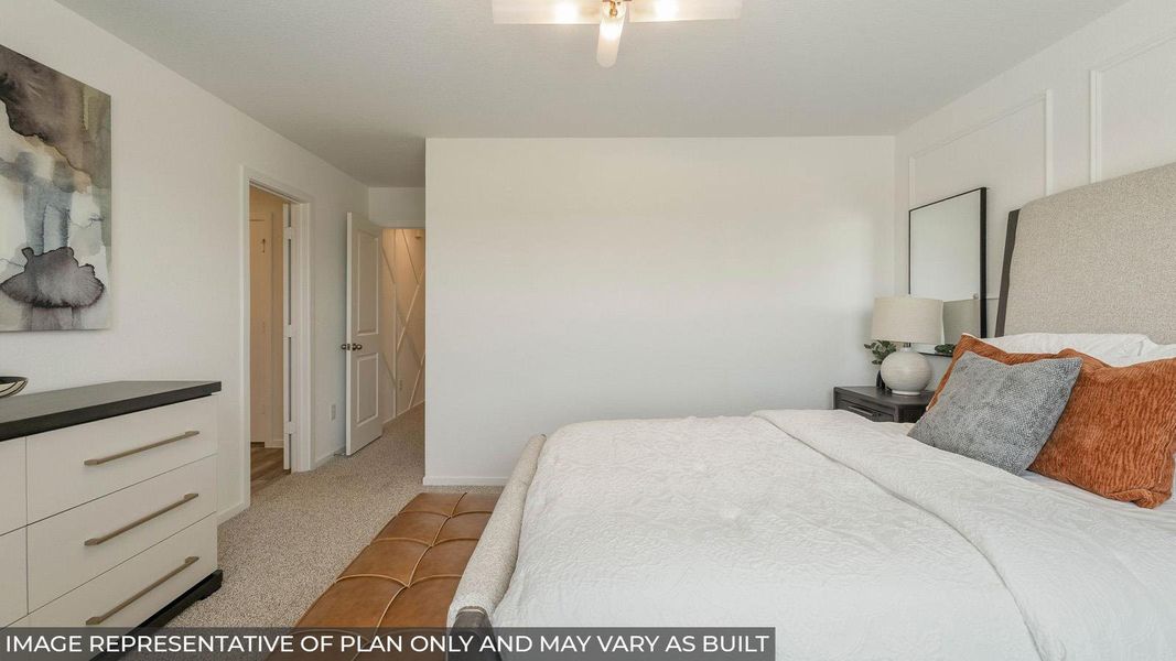 Carpeted bedroom featuring an upholstered headboard, a ceiling fan with light fixture, and a paneled accent wall
