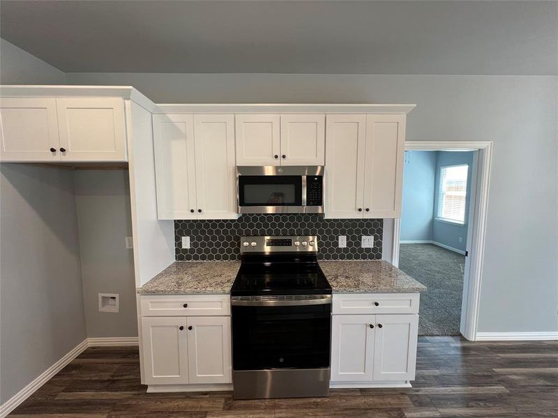 Kitchen featuring white cabinetry, light stone countertops, and appliances with stainless steel finishes