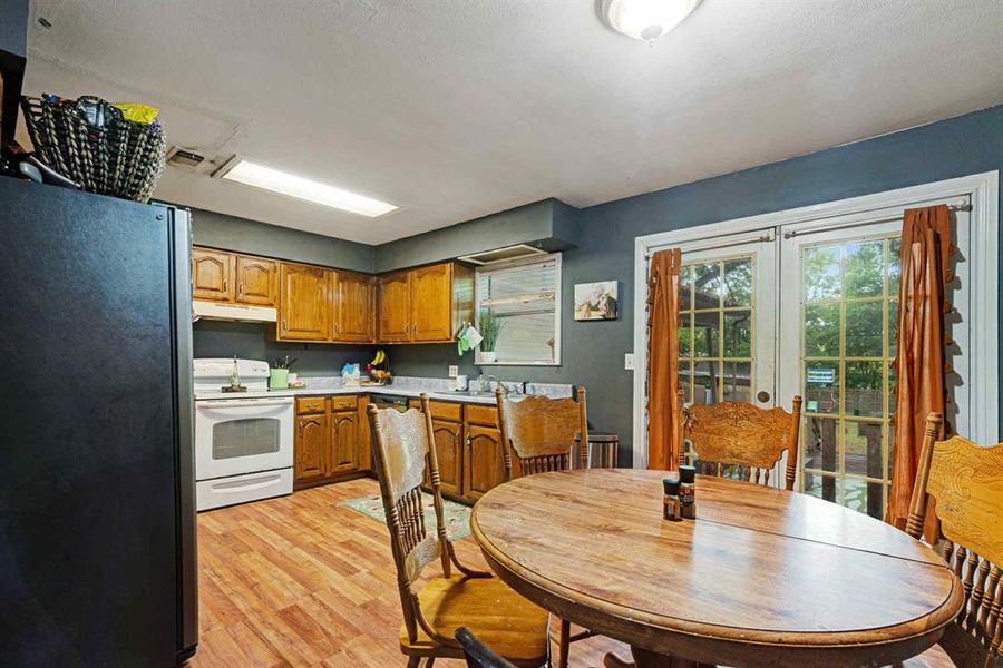 Kitchen with freestanding refrigerator, french doors, white electric stove, light countertops, and brown cabinets Kitchen with freestanding refrigerator, french doors, white electric stove, light countertops, and brown cabinets