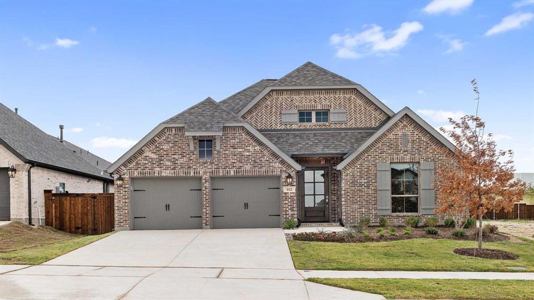 View of front facade featuring a front yard and a garage