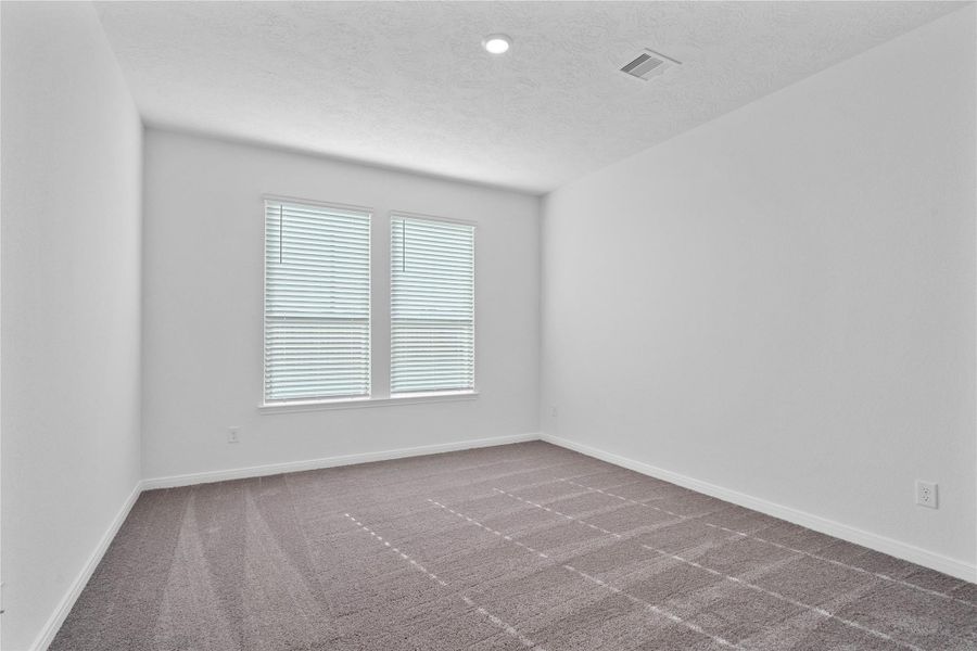 Relax and unwind after a long day in this impressive primary suite! This generously sized room offers plush carpeting, custom neutral paint, high ceilings, recessed lighting, and large windows with privacy blinds for added comfort and tranquility.