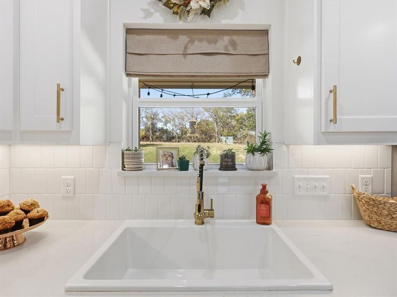 Kitchen view of tasteful backsplash and white cabinetry