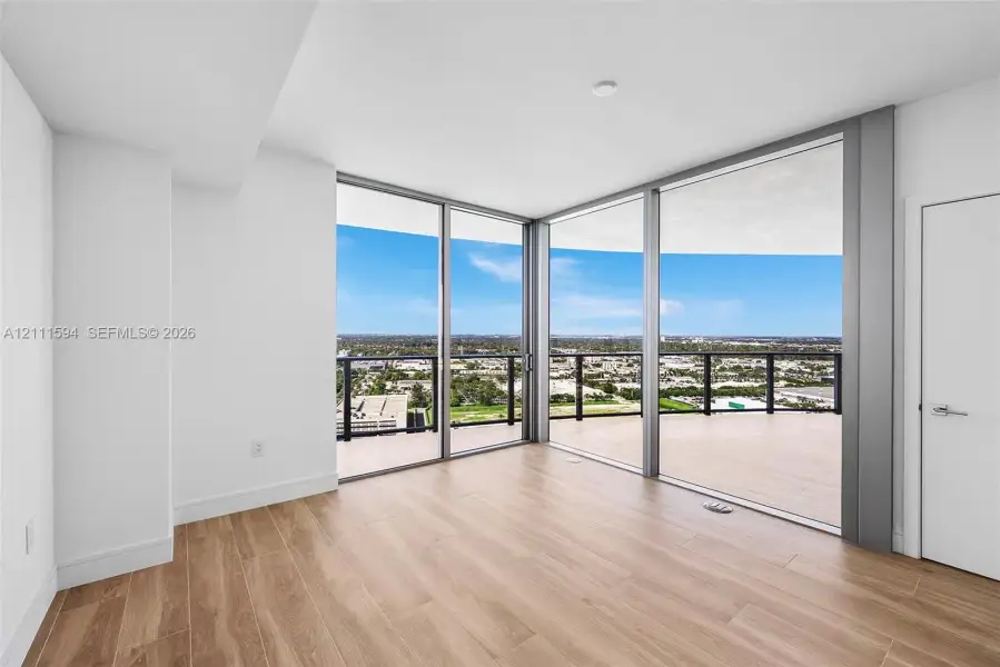 Floor-to-ceiling glass corner walls, wood-finish flooring, and expansive wrap-around balcony with metal railings Floor-to-ceiling glass corner walls, wood-finish flooring, and expansive wrap-around balcony with metal railings