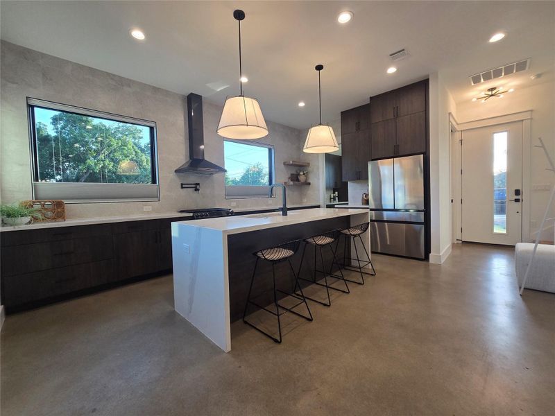 Polished concrete floors and a waterfall-edge island anchor this modern open kitchen.