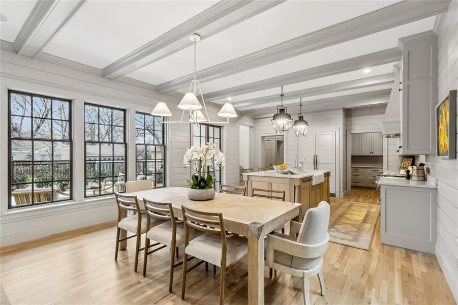 Dining room featuring baseboards, ornamental molding, beam ceiling, and light wood-style floors