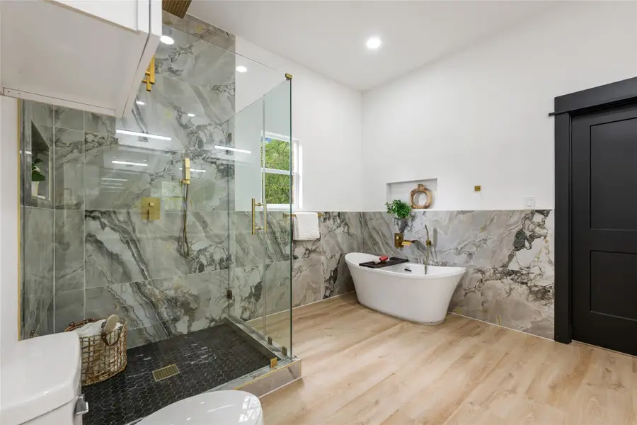 Full bathroom featuring tile walls, a soaking tub, a marble finish shower, wainscoting, and recessed lighting Full bathroom featuring tile walls, a soaking tub, a marble finish shower, wainscoting, and recessed lighting