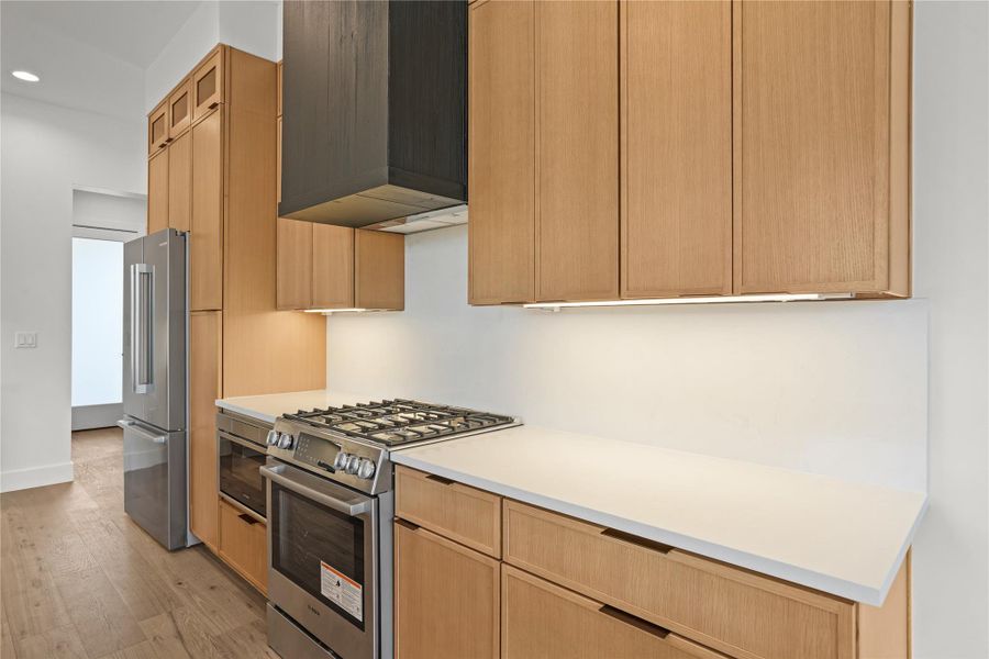 Modern kitchen with streamlined cabinetry, built-in appliances, and light wood flooring.