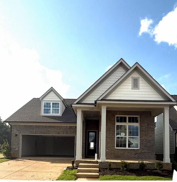 View of front facade featuring brick siding, concrete driveway, a porch, a shingled roof, and a front lawn