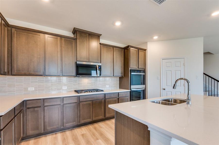 Kitchen with light wood finished floors, light countertops, stainless steel appliances, recessed lighting, and tasteful backsplash