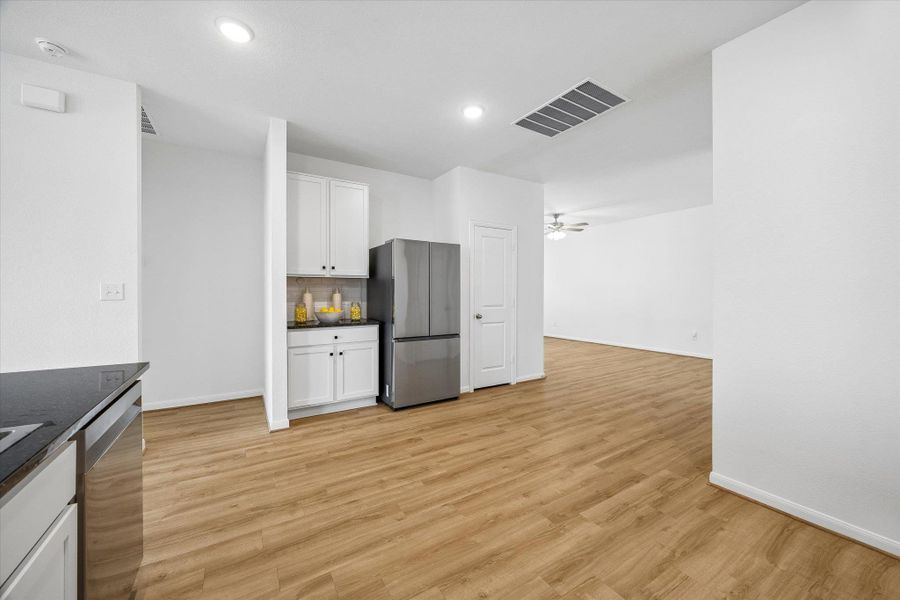 Kitchen featuring white cabinets, stainless steel appliances, light wood finished floors, ceiling fan, and decorative backsplash