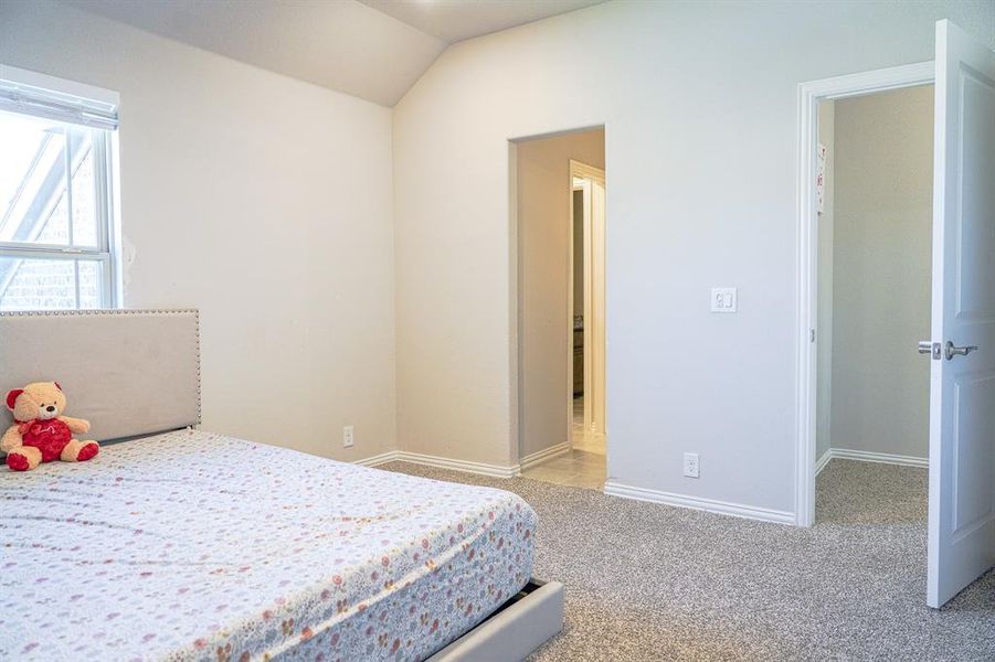Bedroom featuring light carpet and vaulted ceiling