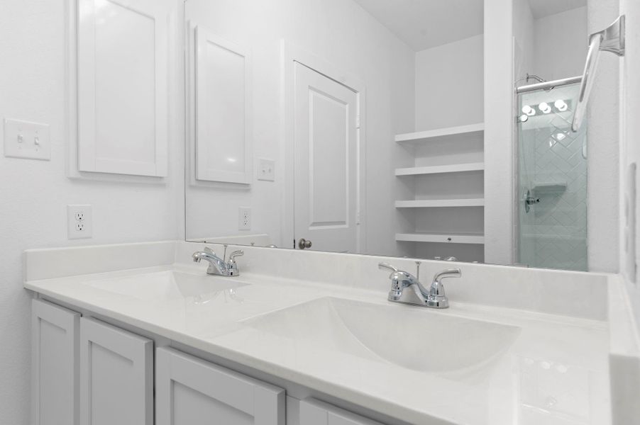 A true spa-like experience awaits in this thoughtfully designed primary bathroom. Dual vanities, ample built-in shelving, and elegant lighting make it both beautiful and functional for everyday luxury. A true spa-like experience awaits in this thoughtfully designed primary bathroom. Dual vanities, ample built-in shelving, and elegant lighting make it both beautiful and functional for everyday luxury.