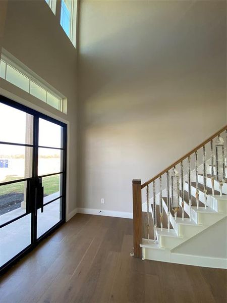 Foyer entrance featuring dark wood-style flooring, stairs, and a towering ceiling