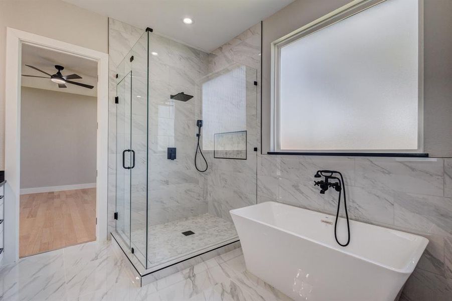 Modern bathroom featuring a freestanding soaking tub, a frameless glass shower enclosure, and large format marble-look tile flooring